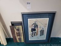 Three framed art prints leaning against a wall, one with visible hockey imagery and blue matting.