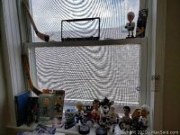 Photo of various hockey bobbleheads, miniature hockey sticks, and collector pucks arranged on a window sill with a Toronto Maple Leafs license plate holder.