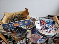 Collection of hockey plates arranged on a wire rack, showing colorful hockey-themed artwork and part of a wooden box holding plate hangers.