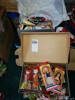 Box showing three boxed dolls, including a pair in red and gold traditional costumes with face masks and two dolls in original packaging with traditional dresses.