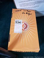 Closed orange box with handwritten note stating '2005 in bags No bags' and auction label