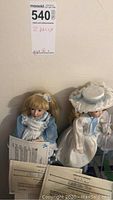Two Danbury Mint porcelain dolls, Alice in Wonderland and Little Bo Peep, with visible Certificates of Authenticity.