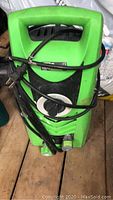 Green Toutch PW1600 electric pressure washer showing front, power cord, and hose attachments, placed on wooden floor