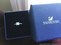 Swarovski ring in blue branded ring box, showing princess cut square crystal center stone with inlaid side crystals.
