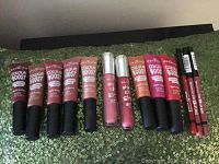 Full set of lipsticks, glosses, and liners displayed on green sequin fabric.
