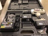 Porter Cable cordless drill with attached battery, second battery, charger and cables inside fitted black molded carry case.