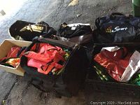 Photo showing multiple sports bags, duffel style, and a box with colorful reusable bags inside.