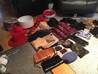 Photo of vintage hats, gloves, handbags, scarves, shawls, and other accessories laid out on the floor and a couch, showing the assortment and variety of items.