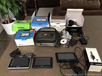 Photo showing three GPS units - Sony Nav-u, Garmin Nuvi 44 and Garmin Nuvi 55 - all with accessories such as chargers, power cables, mounting brackets, software CDs and Case Logic travel bag.