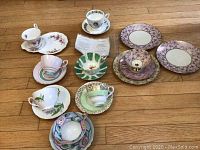 Photo showing all vintage tea cups, saucers, and side plates arranged on wooden floor