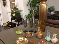 Overview of all glass pieces including carnival glass items, Vaseline glass bowl, Caithness art glass vases, art glass flutes, and tall vase with metallic sheen.
