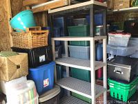Shelving unit shown with various storage bins around it, wood shed background