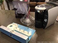 Photo of Bosch Tassimo coffee machine, glass wine decanter in box, and wood key holder on a countertop.