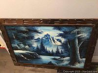 Front view of the oil painting showing northern mountain landscape with trees and water, framed in carved wood.