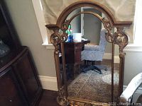 Full view of large ornate decorative mirror showing the arched top and wooden scrollwork frame. Provides overall size and detail of woodwork.