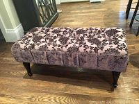 Top and front side view of the tufted floral patterned fabric decor bench with removable dark wooden legs.