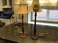 Two decorative lamps on a kitchen island, showing entire lamps including shades and cords.