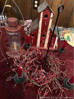 Photo showing the red wooden birdhouse with white beams, the red metal lantern, and the chandelier decorated with cranberry berry branches and candles.