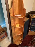 Front view of the wooden corner shelf showing all five triangular shelves and the curved top design
