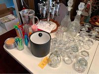 Table display of crystal decanters, multiple glasses, colorful stir sticks, ice bucket, and pitchers.