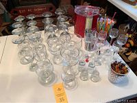 Wide overview of collection showing multiple types of bar glasses, stirring sticks, an ice bucket, and bowl of utensils.
