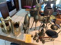 Overall lot view on table showing two brass swans, two brass deer, multiple brass bells and bell snuffer.