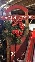 Close-up of wooden sled decoration with 'Welcome' sign and festive wreath