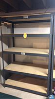 Full view of shelving unit showing 5 particle board shelves supported by black metal frame.