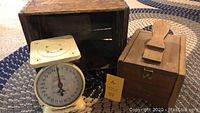 Photo showing the three items: vintage shoe shine box, wooden crate, and American Family kitchen scale on braided rug