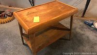 View of wooden Mid Century side table from a side angle showing top surface and lower shelf.