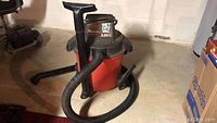 Full view of Craftsman 12 gallon wet dry vacuum with hose, red body, black top and wheels.