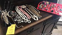 Overview of assorted costume necklaces, bracelets, and rings on display including pearl-like bead strands and chain necklaces