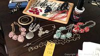 Full assortment of costume jewelry pieces including several statement necklaces with gemstones and various bracelets on table and tray.