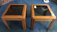 Pair of oak side tables with tinted glass tops shown from above in living room carpeted floor.