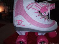Side view of one roller skate showing white and pink material with pink wheels and 'Arctar' branding