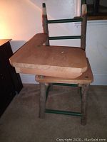 Photo of handmade child's wooden desk and chair stacked with chair upside down on top of desk showing natural wood and green painted accents.