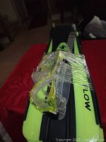 Two pairs of swim flippers and two swim masks wrapped together on a red surface.