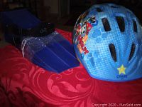 Pair of blue swim fins and the Paw Patrol helmet placed on a red surface, showing fins top side and helmet side view