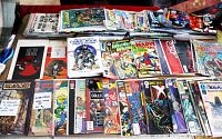 Wide view of multiple bagged comics stacked and fanned out on table with Overstreet price guide visible