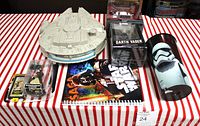 Photo of entire Star Wars collection laid out on striped tablecloth showing all items including the Millennium Falcon Micro Machines spaceship, Finn Elite Series figure in packaging, Darth Vader figurine box, Obi-Wan Kenobi figure, collector cup, and calendar.