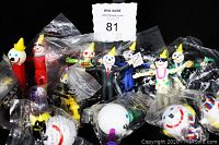 Photo of 14 vintage Jack In The Box collectibles including PEZ dispenser, action figures, and antenna balls mostly sealed in plastic.