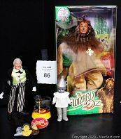 Photo of Wizard of Oz collectible figures including 75th Anniversary Cowardly Lion doll in box, 1973 Mego Wizard figure, Toto resin figurine, magnets, and Madame Alexander Tin Man figure.