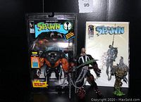 Photo showing the 1994 Tremor Spawn figure sealed in original blister packaging alongside two loose Spawn figures and the Spawn #30 comic book.