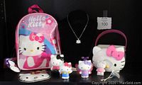 Photo showing entire Hello Kitty collectibles lot with pink backpack, rhinestone necklace on display, white tote bag shaped as Hello Kitty face, purse, bracelet/necklace and assorted figurines.
