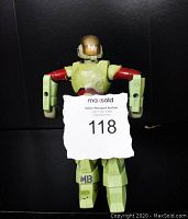 Front view of Robotech Cyclone Scott Bernard Mospeada action figure showing wear and paint loss, with identification note held in front.