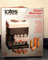 Front view of the Totes Coin Sorter in its original packaging showing product details and images of sorted coins and rolls.