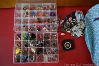 Two plastic cases with various costume jewellery rings organized in compartments, plus a zip lock bag with bracelets and brooches on the side.