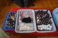Two white baskets and one blue basket filled with many nail polish bottles, a nail extension kit with false tips, black bag of glue, on red surface.