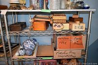 Metal shelving with multiple wooden boxes of different sizes and styles on two shelves. Porcelain decorative balls on lower shelf with cardboard boxes labeled for porcelain items.
