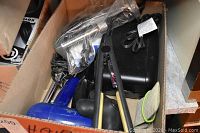 Hair styling tools packed in a box including hair dryer, straightener, curler, clips, and power adapter with some showing wear and tear.